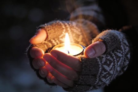 Руки, що захищають джерело світла від темряви, як символ надії та стійкості під час блекауту